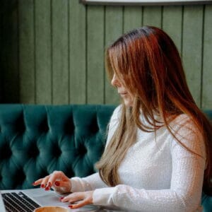 Anne-Marie Mayers working on her laptop in a clam creative workspace, symbolising growth and professional development through the ELEVATE holistic coaching course bundle.